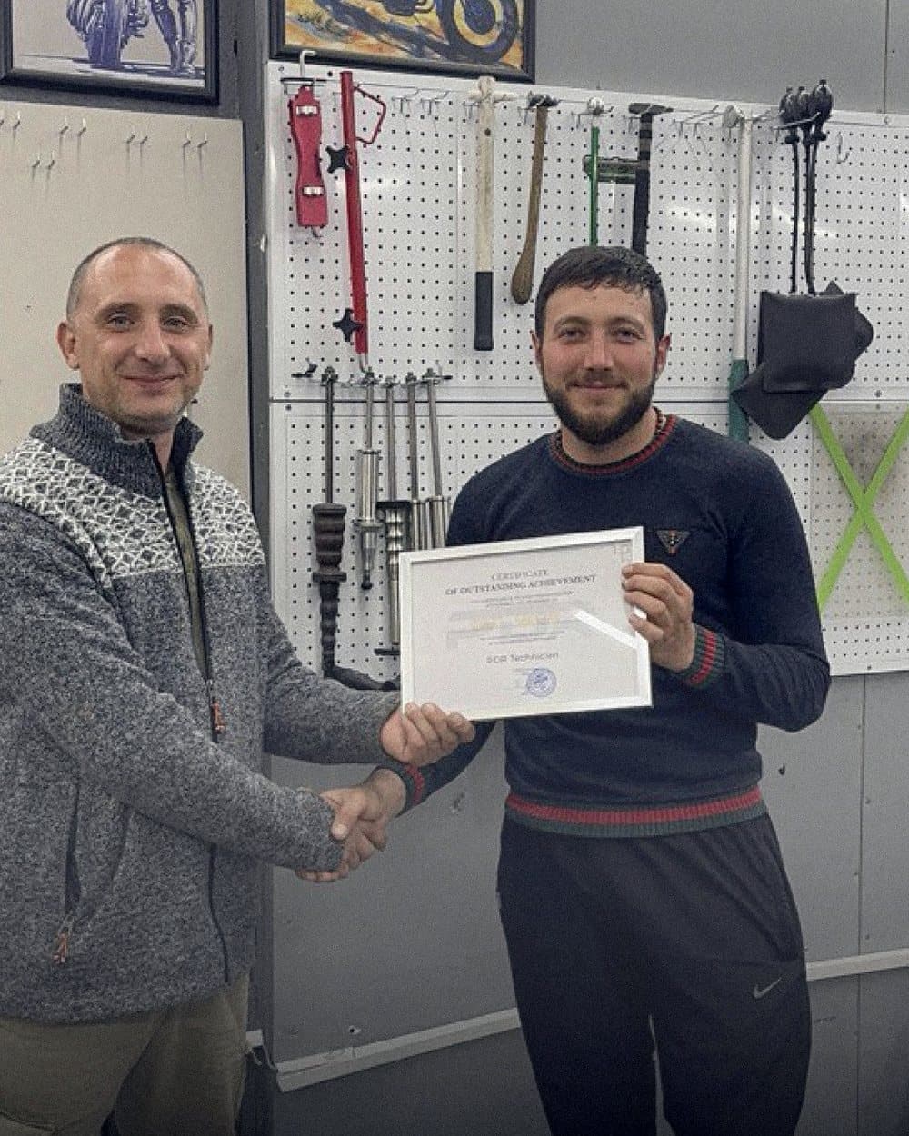 ოსტატი კურსდამთავრებულს სერტიფიკატს გადასცემს